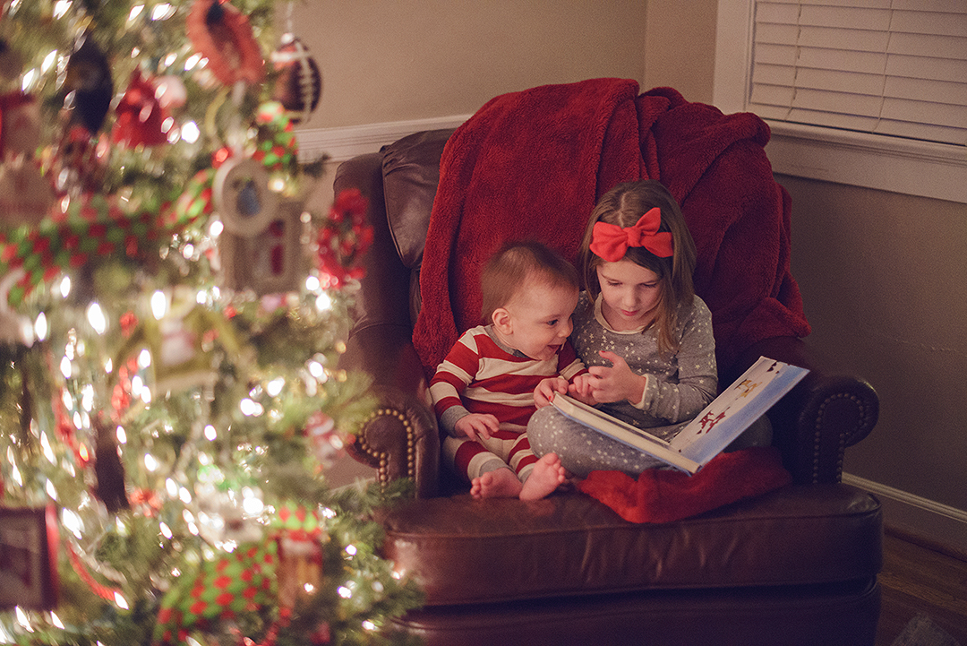 Children reading a book at Christmas time while sitting next to a Chrstmas tree | St. Louis Mini Session Photographer | Fresh Art Photography | Jodie Allen